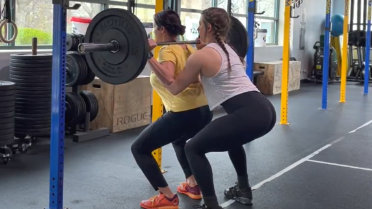 Chica ayudando en la sentadilla